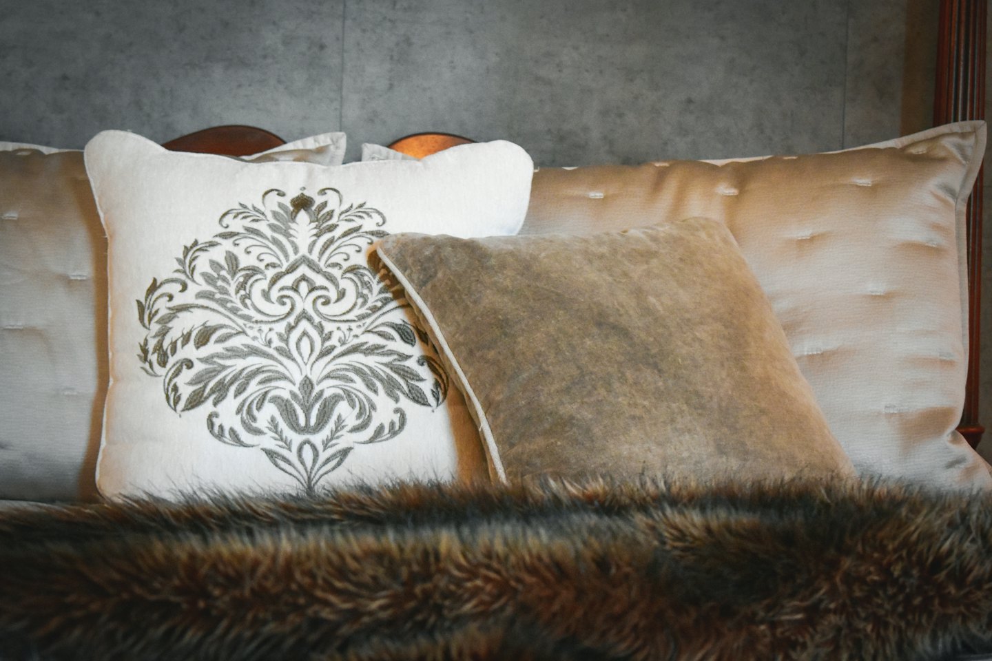 Cuscini decorativi e una coperta in finta pelliccia su un letto.